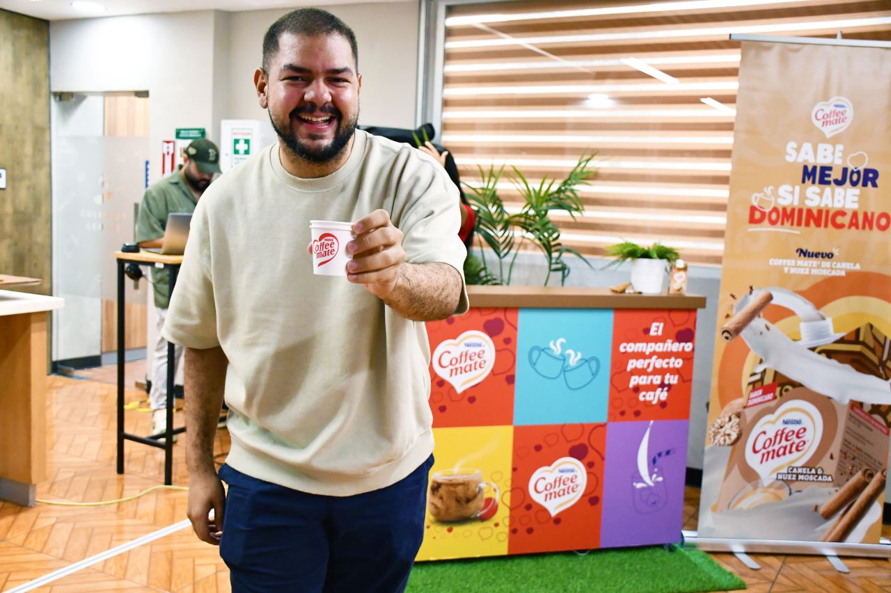Hombre sonriendo sosteniendo un vaso con el logo de Coffee Mate